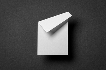White blank paper note cardboard with folded corner dog-ear earmark, shadow and copy space for text on black gray background