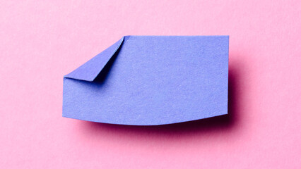 Blue blank paper note cardboard with folded corner dog-ear earmark, shadow and copy space for text on pink background