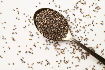 Dry chia seeds in an aged metal spoon on white background. Organic, healthy chia seeds, rich in omega-3, protein, and vitamins. Superfood, food background with space for text