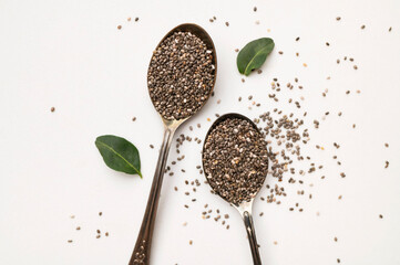 Dry chia seeds in an aged metal spoon on white background. Organic, healthy chia seeds, rich in omega-3, protein, and vitamins. Superfood, food background with space for text
