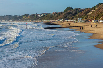West Cliff Beach, Bournemouth, UK - December 25th 2025: A few people on the sandy beach on Christmas Day.