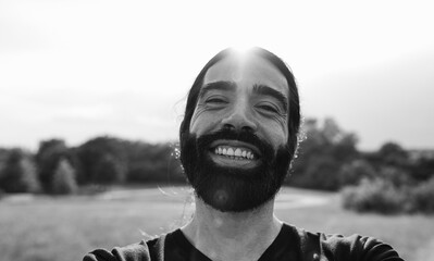 Young happy man smiling on camera before morning sport routine outdoor - Focus on mouth - Black and...