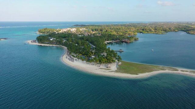 Drone overhead view of the beach of Constance Belle Mare Plage in Mauritius, with palm trees, umbrellas and a beautiful turquoise sea with transparent water. Luxury 5 star hotel in Mauritius.