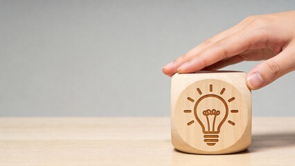 Hand holding wooden cube with lightbulb