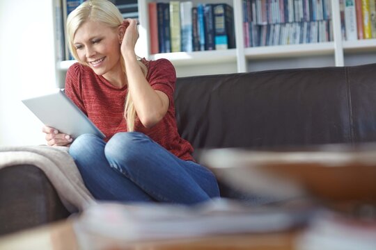 Woman, home and tablet on sofa with video call or online shopping with a smile. Living room, happy and internet sale with digital, tech and website in a lounge with social media and download - Powered by Adobe