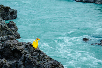 Woman in yellow dress on rocky shore with turquoise waves of Katun river Altay Russia