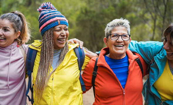 Multiracial women having fun during trekking day into the wood - Escape to the nature and travel concept - Main focus on center faces