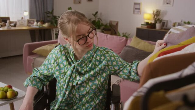 Caucasian young woman with disability wearing glasses choosing blouse from clothing rack while getting ready for going out