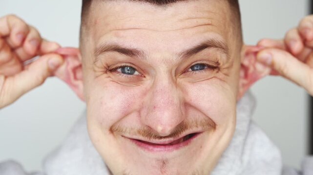 A guy's funny facial expression.
A cheerful and funny man grimacing and having fun in front of the camera.
A man with a strange facial expression.