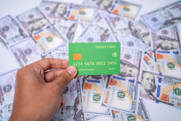 Hand Holding Green Credit Card Over Dollar Bills