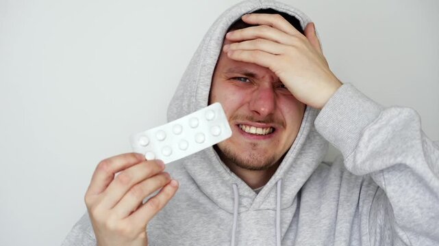 Painkiller tablets in the hands of a man with a headache.
Dizziness and fatigue.
The man takes headache medication.