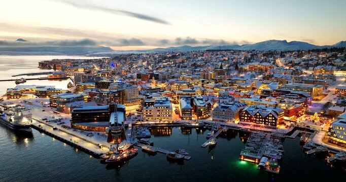 Twilight aerial view over harbor of cozy illuminated snowy streets of Tromso