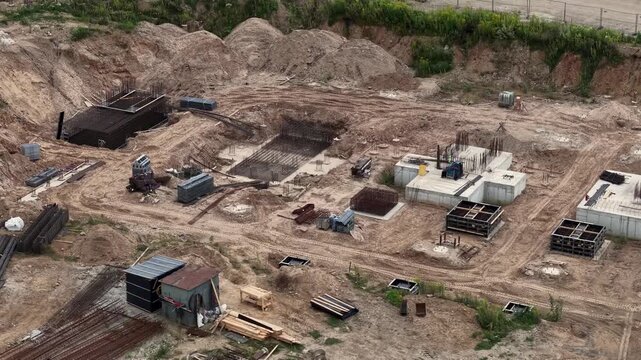 Drone flyover of Vilnius National Stadium construction showing concrete foundation pads, rebar cages, formwork and excavation earthworks on a large urban infrastructure build - 16 August 2025