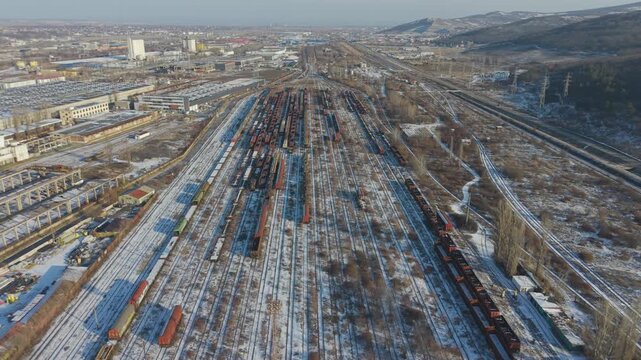 Drone footage showing a panoramic view of a railway freight station and industrial area during a cold winter day
