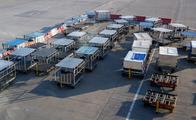 Empty luggage carts and baggage trailers parked on the airport tarmac.