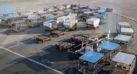 Empty luggage carts and baggage trailers parked on the airport tarmac.