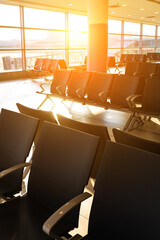 Modern airport waiting area with rows of empty seats at sunset.