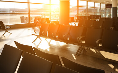 Modern airport waiting area with rows of empty seats at sunset.