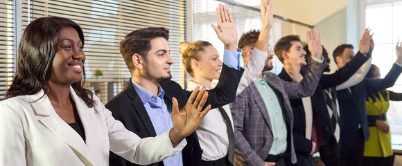 Business team people raise hands in seminar. A diverse group in training at the office responds to a question, signaling a vote with confidence. Concept of engagement and active participation.