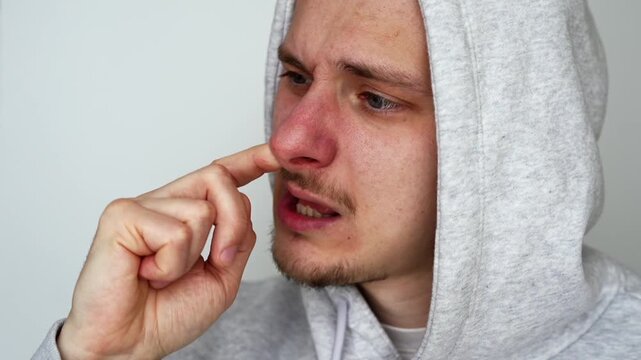 The rude and uncivilized behavior of a guy picking his nose against a white background.
A rude guy with nasty habits.