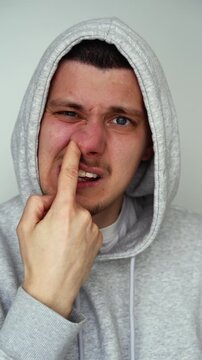 The rude and uncivilized behavior of a guy picking his nose against a white background.
A rude guy with nasty habits.