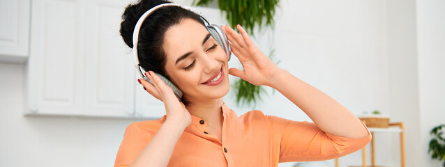 Naklejka premium Joyful young woman enjoying music while sprucing up her stylish apartment