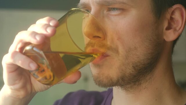 Taster assesses beverage, Focused person samples drink carefully, Individual evaluates flavor and texture meticulously, Person with concentrated expression tastes amber tonic closely examining