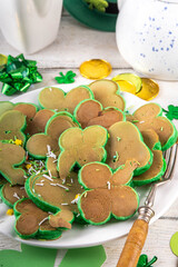 Shamrock shaped green tasty sweet pancakes for St Patricks day breakfast. Creative homemade tasty fried pan cakes with sugar sprinkles and Saint Patrick holiday decor