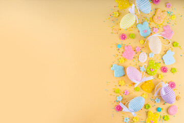 Cute and bright pastel colored Easter eggs and bunny background. Pink. blue, yellow colored bunny rabbits, eggs and flowers sugar sprinkles on light yellow background