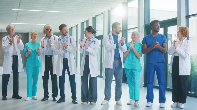 Medical team standing in white hospital hall clapping together. Smiling and encouraging each other. Celebrating progress and showing unity while supporting positive atmosphere. Bright sunlight.