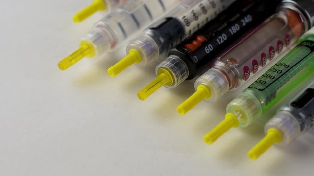 Close-up of diabetic insulin pens and syringes with measurement scale on a light background. Medical devices used for insulin injection and diabetes management