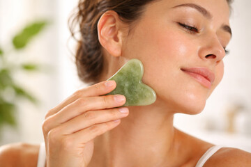 Young woman using heart-shaped jade roller for skincare routine