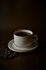 A cup of coffee and coffee beans on a dark background.