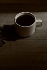 A cup of coffee on a wooden table and under the morning light.