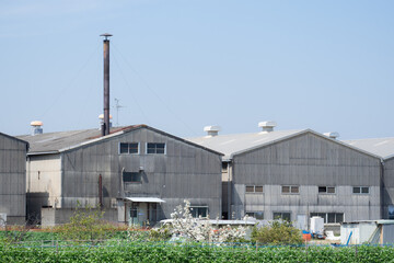 青空にそびえる煙突とスレート屋根の町工場、ノスタルジックな日本の工業風景