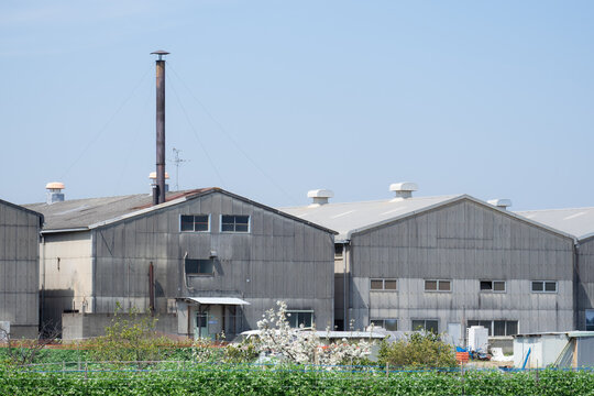 青空にそびえる煙突とスレート屋根の町工場、ノスタルジックな日本の工業風景
