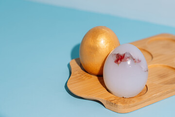 Silicone Easter eggs on wooden board on blue background, minimal still life. High quality photo