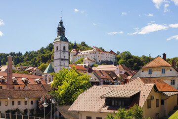 Fototapeta premium Travelers enjoy the historic city center of Skofja Loka with preserved buildings and small town feel, perfect for slow travel experiences.