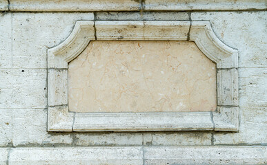 Empty stone plaque set into a classic masonry wall with decorative frame. Architectural detail with...