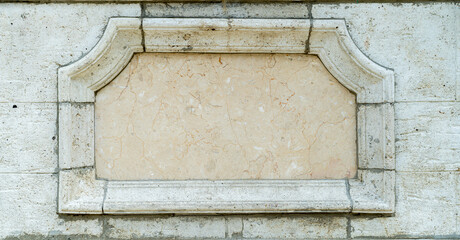 Empty stone plaque set into a classic masonry wall with decorative frame. Architectural detail with...