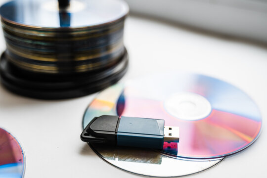 Bunch of CD and DVD discs with USB flash drive placed on them.