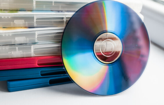 DVD discs in a plastic boxes with a disc in front of them on a white background top view.