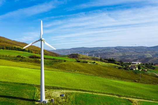 Aerial view of wind turbines harnessing clean power on verdant hills, a symbol of the energy transition and commitment to renewable energy for a sustainable, carbon-free world, Italy.