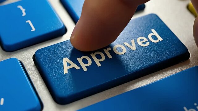 A finger pressing the blue approved button on a modern computer keyboard