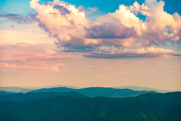 Sunset over layered mountain ridges in the Bieszczady Mountains, seen from Wielka Rawka and Mała Rawka viewpoints. Peaceful nature landscape with dramatic sky and soft evening light.
