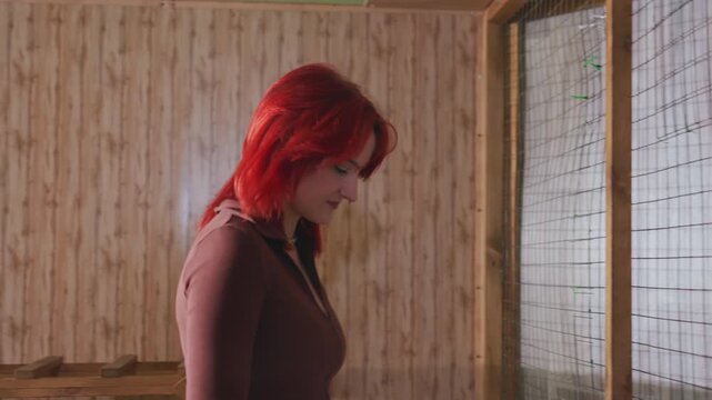 redhaired white woman leaning over cage guiding curious white boy to touch raccoon through wire enclosure in cozy wooden room, gentle supervision, volunteer caregiver role, warm light, educational