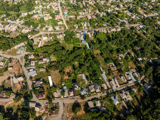 Aerial view captures serene flat suburban residential area enveloped in lush greenery. Daytime scene evokes a peaceful and tranquil atmosphere, highlighting nature's beauty.
