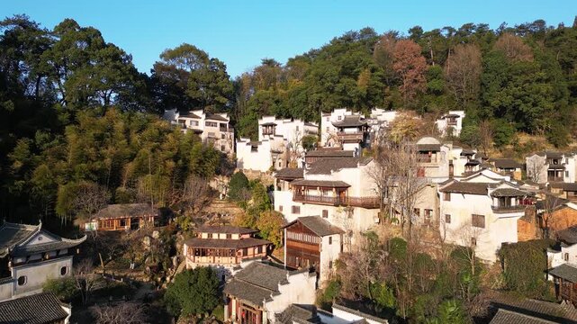 Huangling, China: Aerial backward drone footage of the ancient village of Huangling in the hills in the Wuyuan countryside surrounded by forests on a sunny winter day in China. 