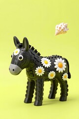 Fototapeta premium Playful Black Toy Donkey Adorned with Daisies Against a Vibrant Yellow Background