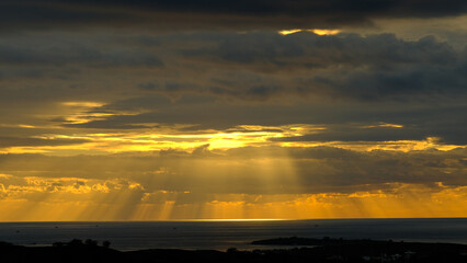 Beautiful sunset at the beach with dancing waves and dramatic clouds reflecting on the water.